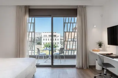 a bedroom with a bed and a desk and a balcony at Athens Hill Luxury Apartments in Athens