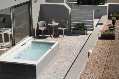 a hot tub on a patio with a table and chairs at Athens Hill Luxury Apartments in Athens