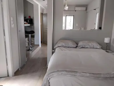 a white bedroom with a bed and a mirror at Roofgarden Apartment in Athens