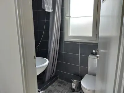 a bathroom with a toilet and a sink and a window at Roofgarden Apartment in Athens