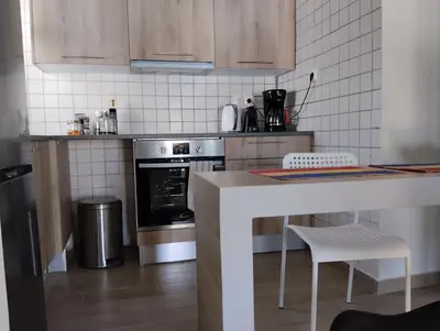 a kitchen with a stove and a counter with chairs at Roofgarden Apartment in Athens