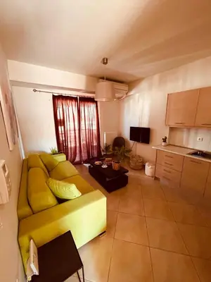 a living room with a yellow couch and a kitchen at Central & Comfortable, with Acropolis view in Athens