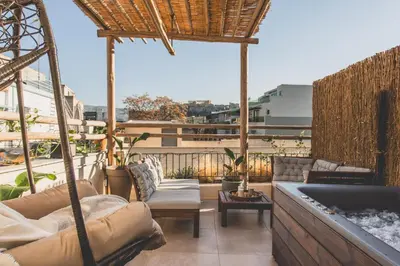 a patio with couches and chairs on a balcony at Luxury Apartment with Acropolis View Terrace and Jacuzzi - Living Stone Moonstone in Athens