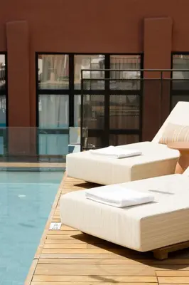 three beds sitting next to a swimming pool at Anise Aluma Athens, Tapestry Collection by Hilton in Athens