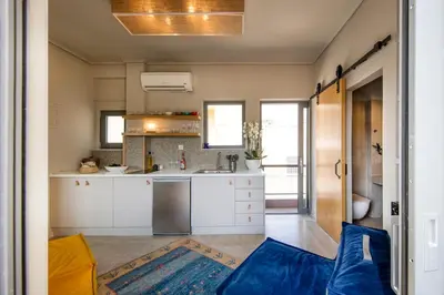 a kitchen with white cabinets and a blue couch at Sunny Loft with Acropolis View in Athens