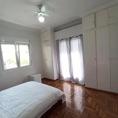 a white bedroom with a bed and two windows at Chrishome in Athens