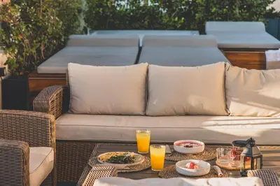 a couch sitting on a patio with a table with drinks at Luxury Apartment with Acropolis view Terrace and Jacuzzi in the Heart of Athens - Living Stone Azurite in Athens