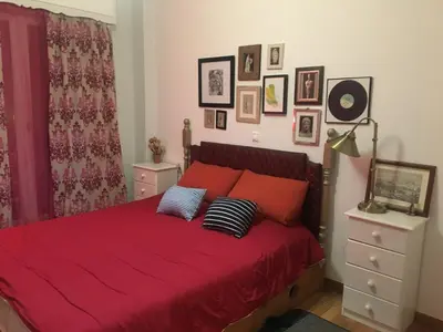a bedroom with a bed with red sheets and pillows at Kouklospito Cozy City Apartment in Kallithea Athens in Athens