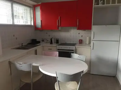 a kitchen with a white table and red cabinets at Cute 1bd Apartment at Vouliagmeni in Athens