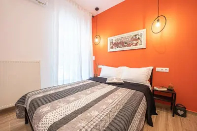 a bedroom with a bed with an orange wall at Calypso Apartment in Athens