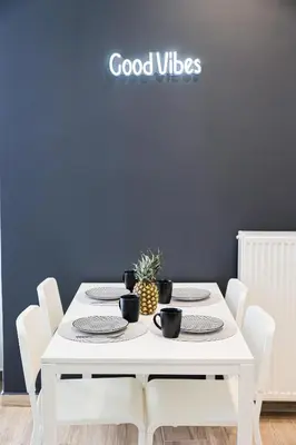 a white table with white chairs and a sign that reads good vibes at Calypso Apartment in Athens