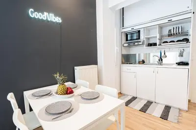 a kitchen and dining room with a white table and chairs at Calypso Apartment in Athens