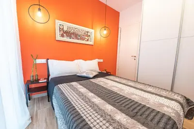 a bedroom with an orange wall and a bed at Calypso Apartment in Athens