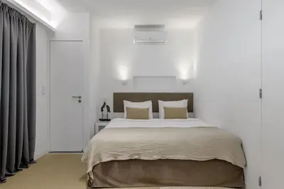 a bedroom with a large bed with white walls at Momo Suites, Acropolis by Aura Homes in Athens