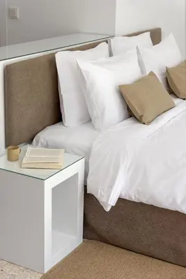 a bed with white pillows and a book on a table at Momo Suites, Acropolis by Aura Homes in Athens