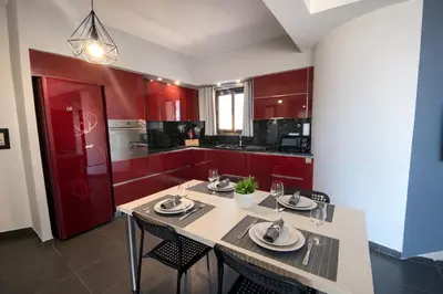 a kitchen with red cabinets and a table and chairs at 5-Star feel - Luxury penthouse for 4 with huge balcony & view ,8 min from Athens airport in Koropíon
