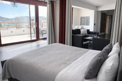 a bedroom with a bed and a view of a balcony at 5-Star feel - Luxury penthouse for 4 with huge balcony & view ,8 min from Athens airport in Koropíon