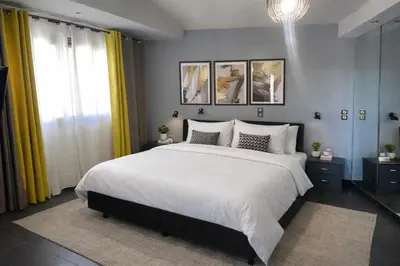 a bedroom with a large white bed with yellow curtains at 5-Star feel - Luxury penthouse for 4 with huge balcony & view ,8 min from Athens airport in Koropíon