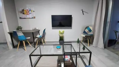 a living room with a table and a tv on a wall at METROPOLITAN MACVIEW-4 ΔΙΑΜΕΡΙΣΜΑ in Piraeus