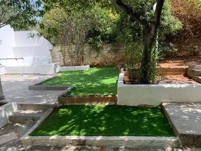 a garden with grass and a tree and stairs at LIVAS Athens Voula garden bungalow in Athens
