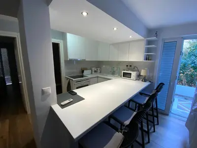 a kitchen with a white counter and some chairs at LIVAS Athens Voula garden bungalow in Athens