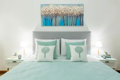 a bed with blue and white pillows and a painting at Nadia’s Boutique Apartment, Athens in Athens