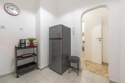a refrigerator in a room with a chair and a clock at Nadia’s Boutique Apartment, Athens in Athens