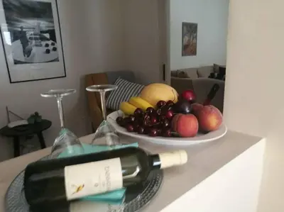 a bottle of wine on a table with a bowl of fruit at Maria's Cozy apartment in Palaio Faliro in Athens