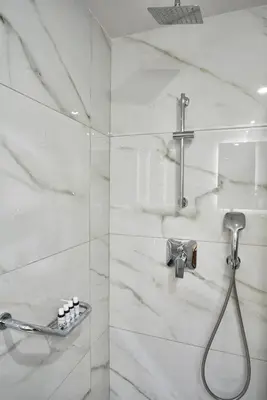 a bathroom with a shower with white marble walls at Chic n Bright 3Bd Apt with Hilton View in Athens