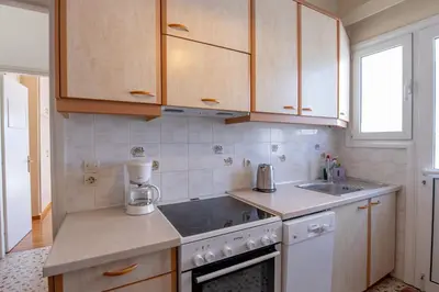 a kitchen with white appliances and wooden cabinets at Alimos Marina Sunnyhub in Athens