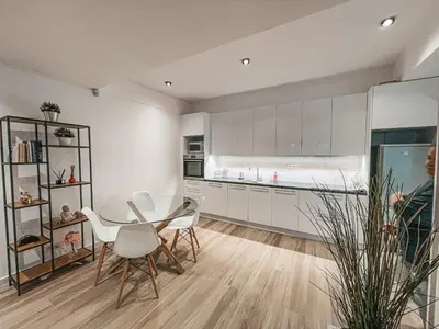 a kitchen with white cabinets and a table and chairs at Pool Voula Apartment close to Kavouri Beach by Cielo Homes in Athens