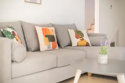 a living room with a gray couch with pillows at Adelos Maisonette Near Vouliagmeni Beach in Athens