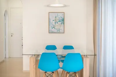 a dining room with a glass table and blue chairs at Adelos Maisonette Near Vouliagmeni Beach in Athens