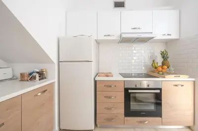 a white refrigerator in a kitchen with wooden cabinets at Adelos Maisonette Near Vouliagmeni Beach in Athens
