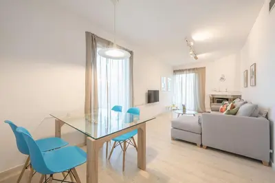 a dining room and living room with a glass table and blue chairs at Adelos Maisonette Near Vouliagmeni Beach in Athens