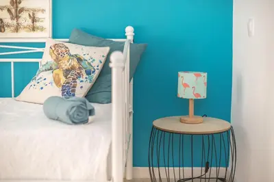 a bedroom with a white bed with a blue wall at Adelos Maisonette Near Vouliagmeni Beach in Athens