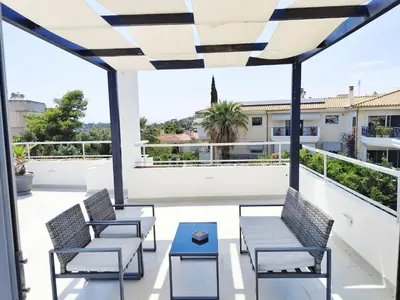 a patio with two chairs and a table on a balcony at Adelos Maisonette Near Vouliagmeni Beach in Athens