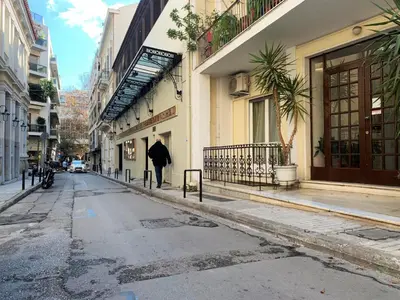 a person walking down a street with an umbrella at GK Aria by GK Properties in Athens