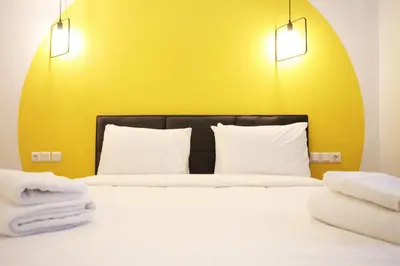 a bed with two white pillows and a yellow wall at GK Aria by GK Properties in Athens