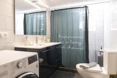a bathroom with a shower curtain with a washing machine at Chalandri Sweet House in Athens