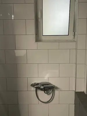 a white tiled bathroom with a shower with a window at Chalandri Sweet House in Athens