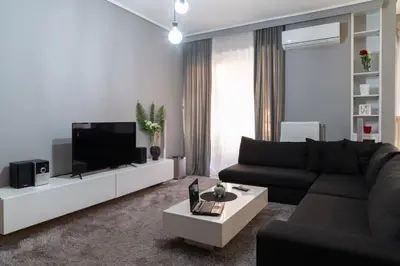 a living room with a black couch and a tv at Chalandri Sweet House in Athens