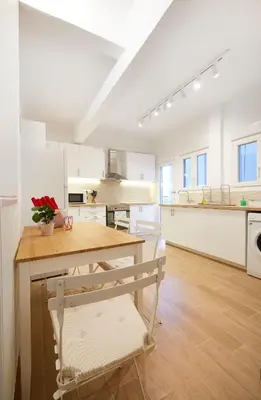 a kitchen with white cabinets and a wooden table at Chloe Boutique Apartments Nikis in Athens