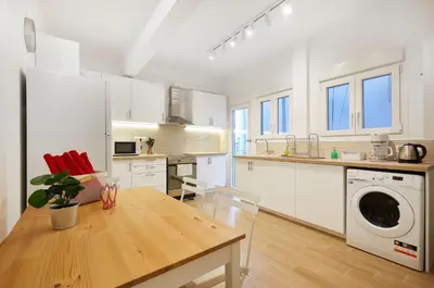 a kitchen with white cabinets and a table with a washer at Chloe Boutique Apartments Nikis in Athens