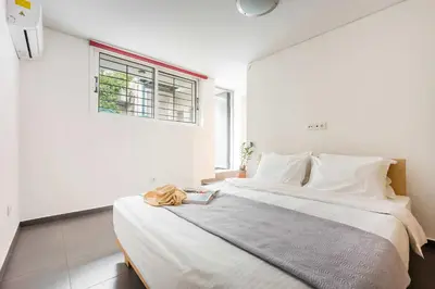 a white bedroom with a bed with a book on it at Stylish 2BR Koukaki l Balcony & Work-Friendly Desk in Athens