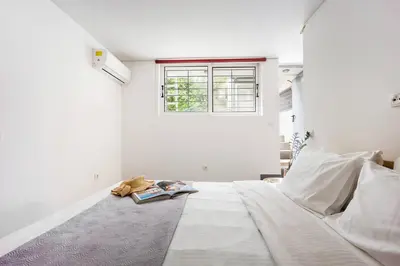 a white room with a bed with a book and a window at Stylish 2BR Koukaki l Balcony & Work-Friendly Desk in Athens