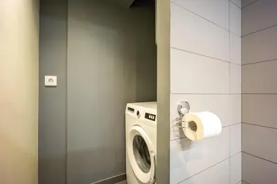 a bathroom with a washing machine and a roll of toilet paper at Stylish 2BR Koukaki l Balcony & Work-Friendly Desk in Athens