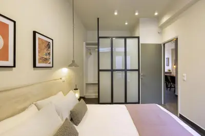 a bedroom with a white bed with a glass door at Α Rare Lux Artistic RENV Gem opposite EMST Museum in Athens