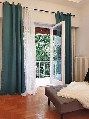 a bedroom with green and white curtains and a window at Acropolis Select Flat in Athens