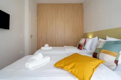 two beds in a room with white sheets and towels at The Athens Gathering, Hip area and sightseeing in Athens